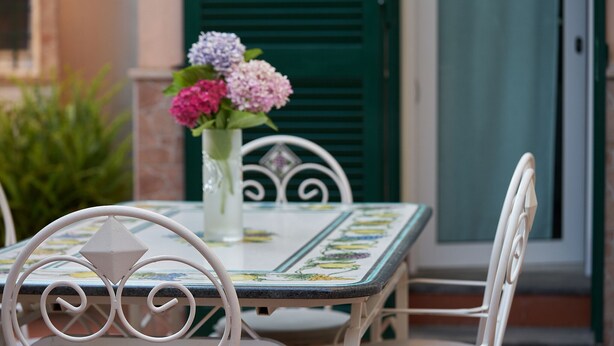 A table with a floral tablecloth and a vase with flowers.