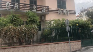 A two-story building with a balcony adorned with white flowers.