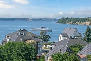 Zona residencial costera con casas y un ferry al fondo.