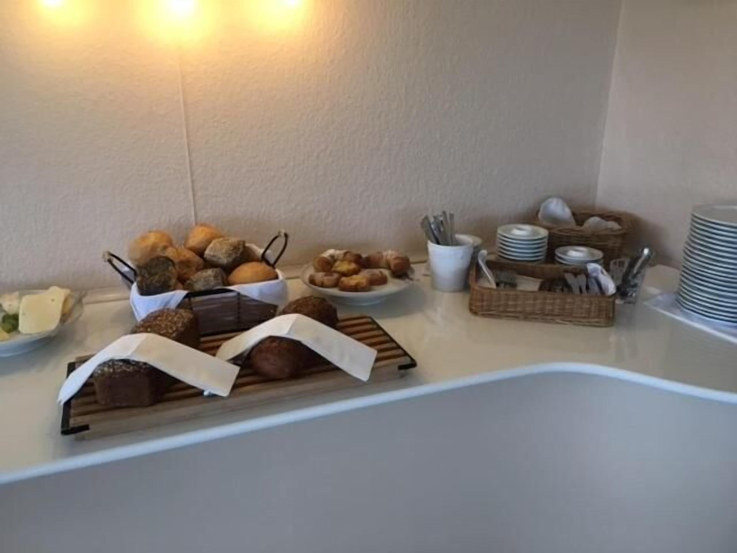 Ein reich gedeckter Buffetstisch mit verschiedenen Backwaren, Tellern und Besteck.
