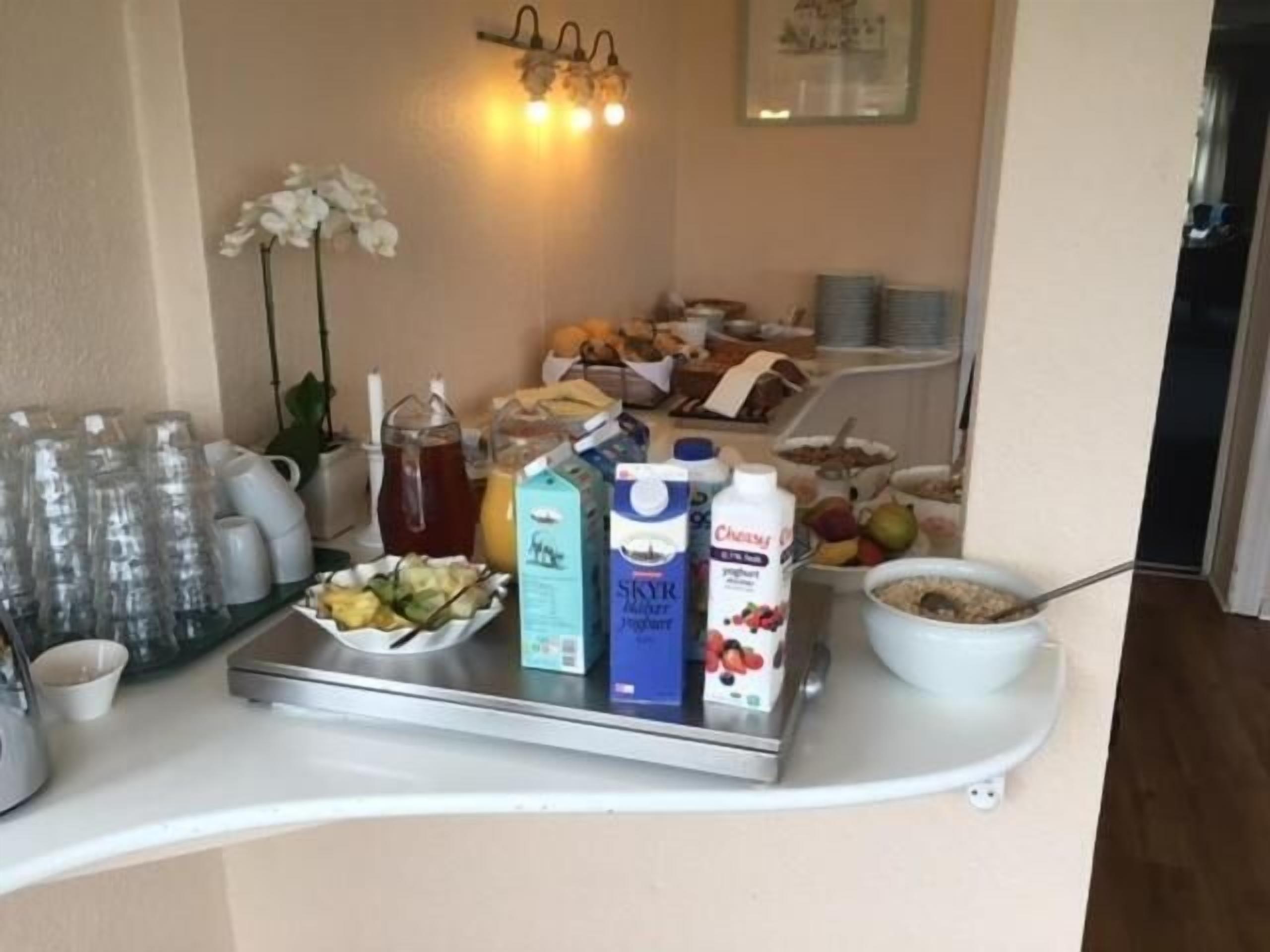 A breakfast buffet setup with various food items, beverages, and a fruit bowl.