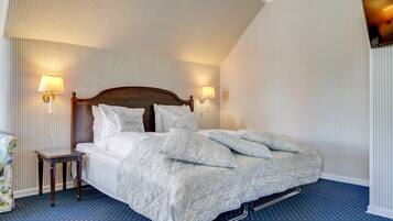 A neatly made bed with a wooden headboard, two bedside lamps, and a small table beside it.