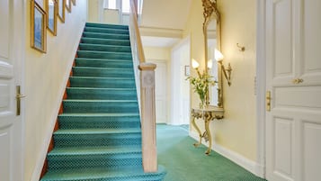A staircase with green carpeted steps, a white door, and a wall-mounted mirror.