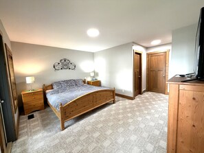 Une chambre à coucher avec un lit en bois, des tables de chevet, un luminaire fixé au mur et une armoire en bois.