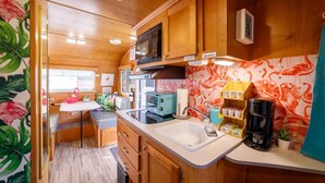 A compact kitchen with wooden cabinets, a microwave, a sink, and a coffee maker. - End of summer fun in Bettie Blue! (El Cajon)
