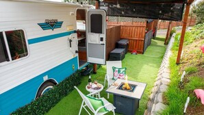 A recreational vehicle with a covered patio area, a small table with chairs, and a fire pit. - End of summer fun in Bettie Blue! (El Cajon)
