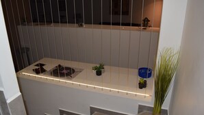 A modern kitchen with a long countertop, hanging plants, and a blue basket.