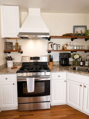 A kitchen with a stainless steel stove, oven, and a coffee maker on the countertop.