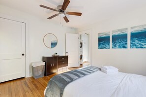 A bedroom with a bed, a ceiling fan, a washing machine, and artwork on the wall. - Chic Craftsman, Walk Downtown (Durham)