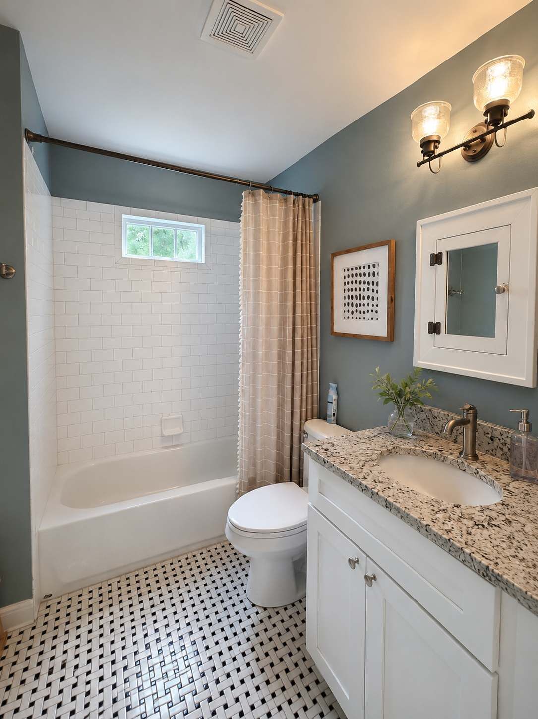 Un baño con una bañera blanca, inodoro, lavabo con encimera de granito y cortina de ducha.