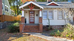A single-story house with a front porch, a red door, and a brick chimney. - Chic Craftsman, Walk Downtown (Durham)