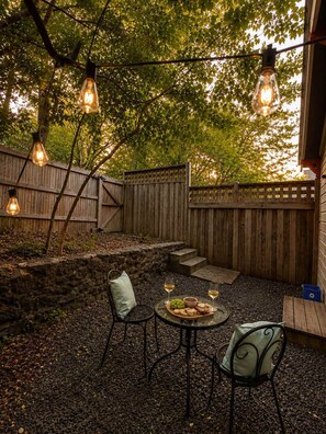 Een terras buiten, met een stenen muur, houten omheining en een gedekte tafel.