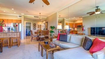 A spacious living room with a large sofa, wooden coffee table, and a dining area with a wooden table and chairs.