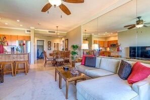 A spacious living room with a large sofa, wooden coffee table, and a dining area with a wooden table and chairs. - Kapalua Golf Villas | Ocean View 1 BR | Car Incl. w/ 6+ Nights | KGV-16T4 by KBM (Lahaina)