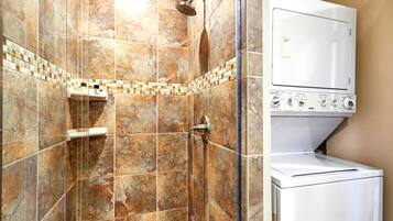 A bathroom with a shower, a toilet, and a built-in washer and dryer.