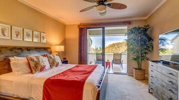 A hotel room with a bed, a ceiling fan, a TV, a dresser, and a balcony with a view.
