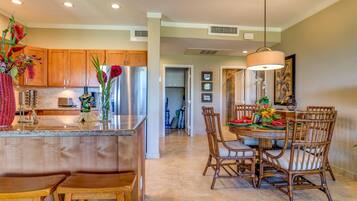 A modern kitchen with wooden cabinets, a stainless steel refrigerator, and a central island with a vase of flowers.