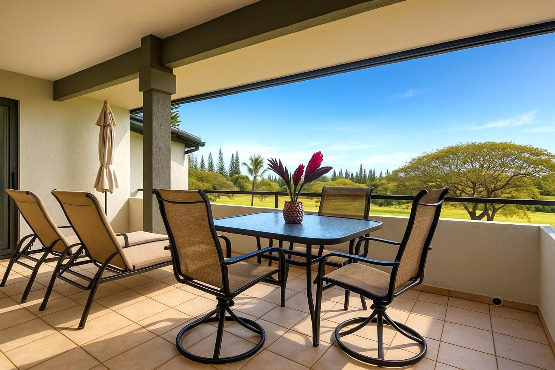 Ein Balkon mit Tisch und Stühlen, einem Blumentopf und Blick auf eine grüne Landschaft.