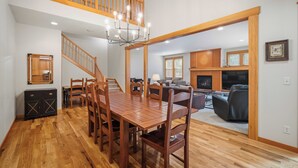 Un'ampia sala da pranzo con tavolo e sedie in legno, un lampadario e una scala che conduce a un piano superiore.