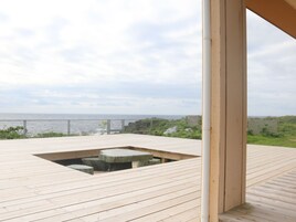 Una terraza de madera con zona de estar de piedra con vistas al mar.