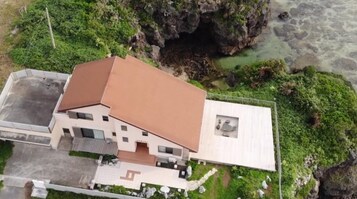 Una casa moderna con techo inclinado, un pequeño garaje adosado y entrada pavimentada.