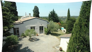 A house with a gravel driveway, a small garden with potted plants, and a view of the surrounding landscape. - Promotions to seize: Beautiful artist cottage, private pool, exceptional view (Peyrefitte-sur-l'Hers)