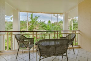 Varanda com móveis de vime e vista para vegetação tropical.