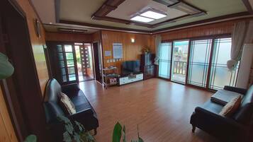 Relax in this spacious living room with a high ceiling, featuring a skylight and comfortable seating for two.