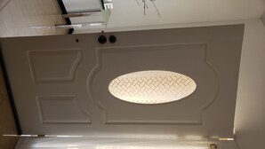 Ett tak med en dekorativ panel, en infälld lampa och en ventilationsöppning.