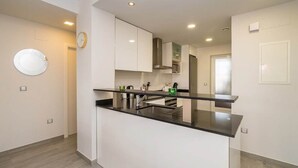 A modern kitchen with white cabinets, a black countertop, and a stainless steel sink. - Apartamento Rosa (Mar de Pulpi) (San Juan de los Terreros)