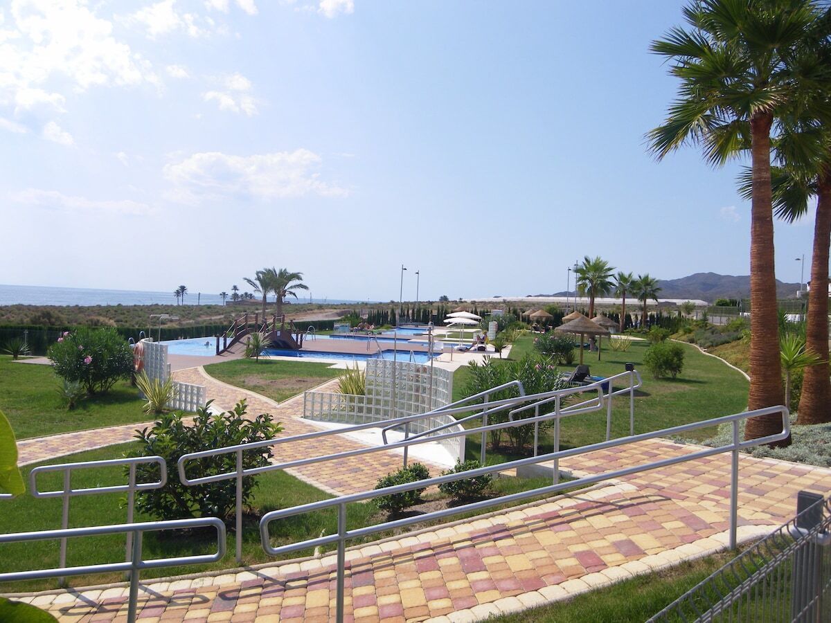 Un complexe hôtelier doté de plusieurs piscines, d’un espace de détente couvert et de palmiers.