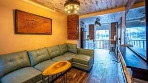 Un salon moderne avec un canapé d’angle, une table basse en bois, une carte accrochée au mur et une vue sur l’extérieur.
