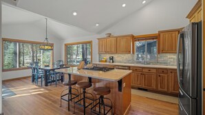Une cuisine moderne avec des meubles en bois, un réfrigérateur en acier inoxydable et un îlot central doté de tabourets de bar.