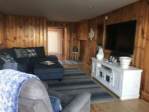 A living room with a sectional sofa, a TV, and a white entertainment unit. - Ocean Front! On the sand!! Stunning 5 BR house on Atlantic Ave, Wells Beach!!! (Wells)