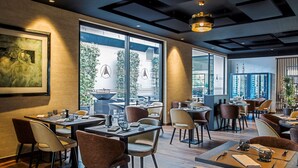 Un restaurante moderno con varias zonas de comedor, ventanas amplias y un diseño de interiores contemporáneo.