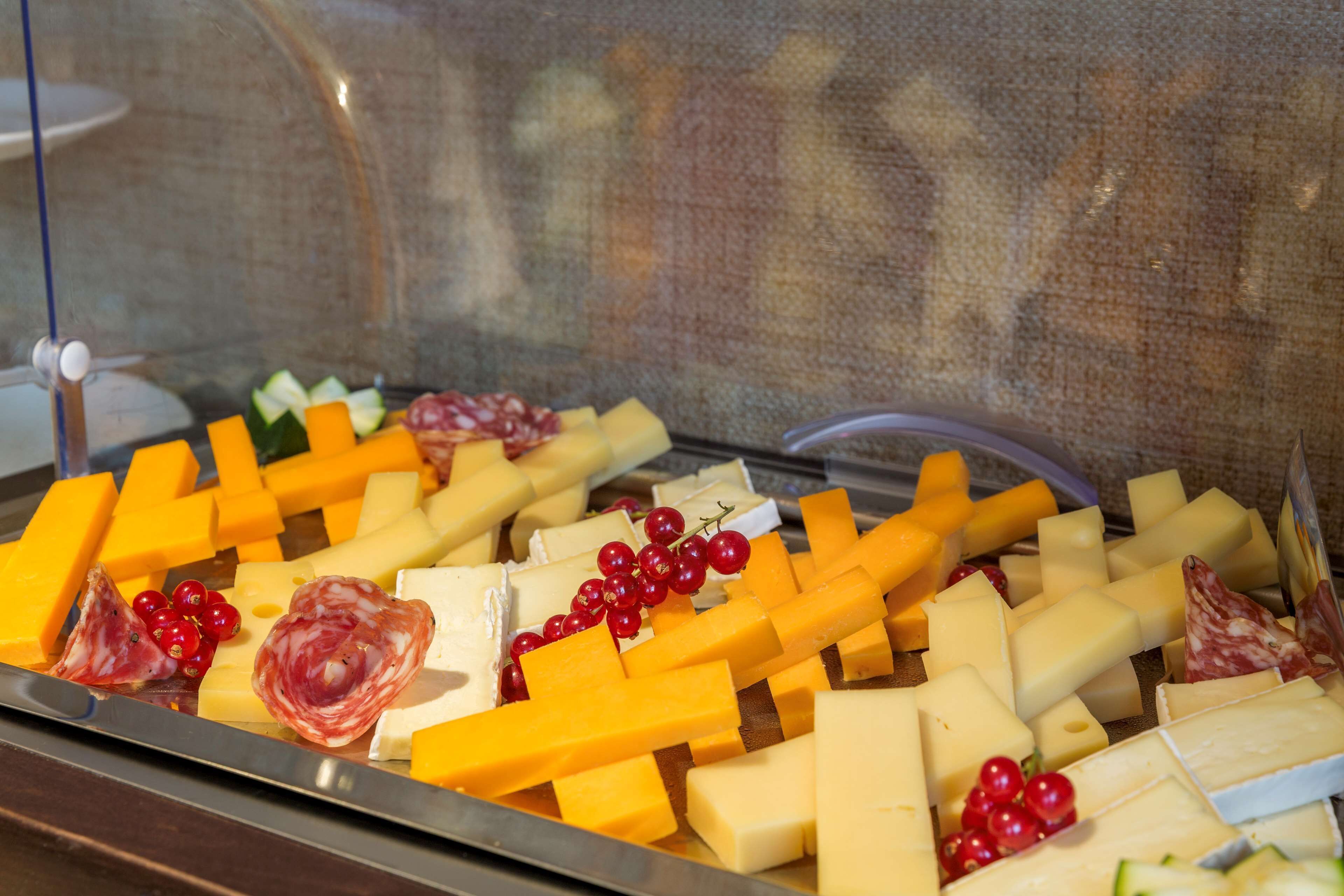 A cheese and meat platter with various types of cheese, cured meats, and red grapes.