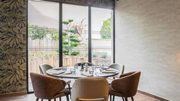A dining area with a round table set for four, surrounded by chairs.