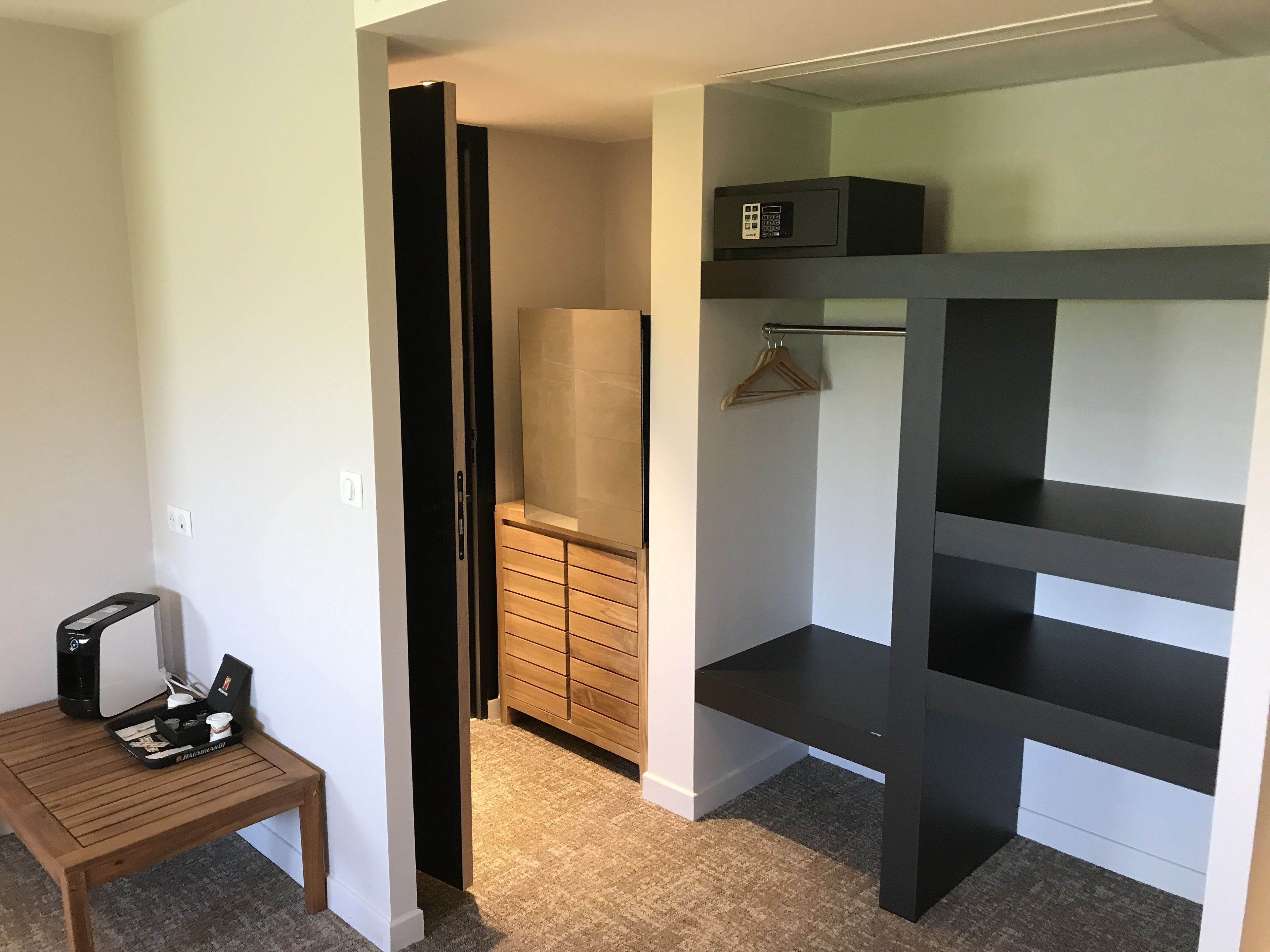 A compact room with a desk, a wardrobe, and a microwave on a shelf.