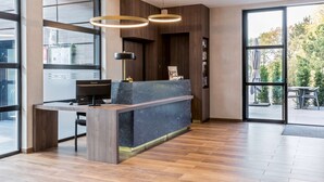 Un moderno mostrador de recepción con encimera de mármol, detalles de madera e iluminación colgante.