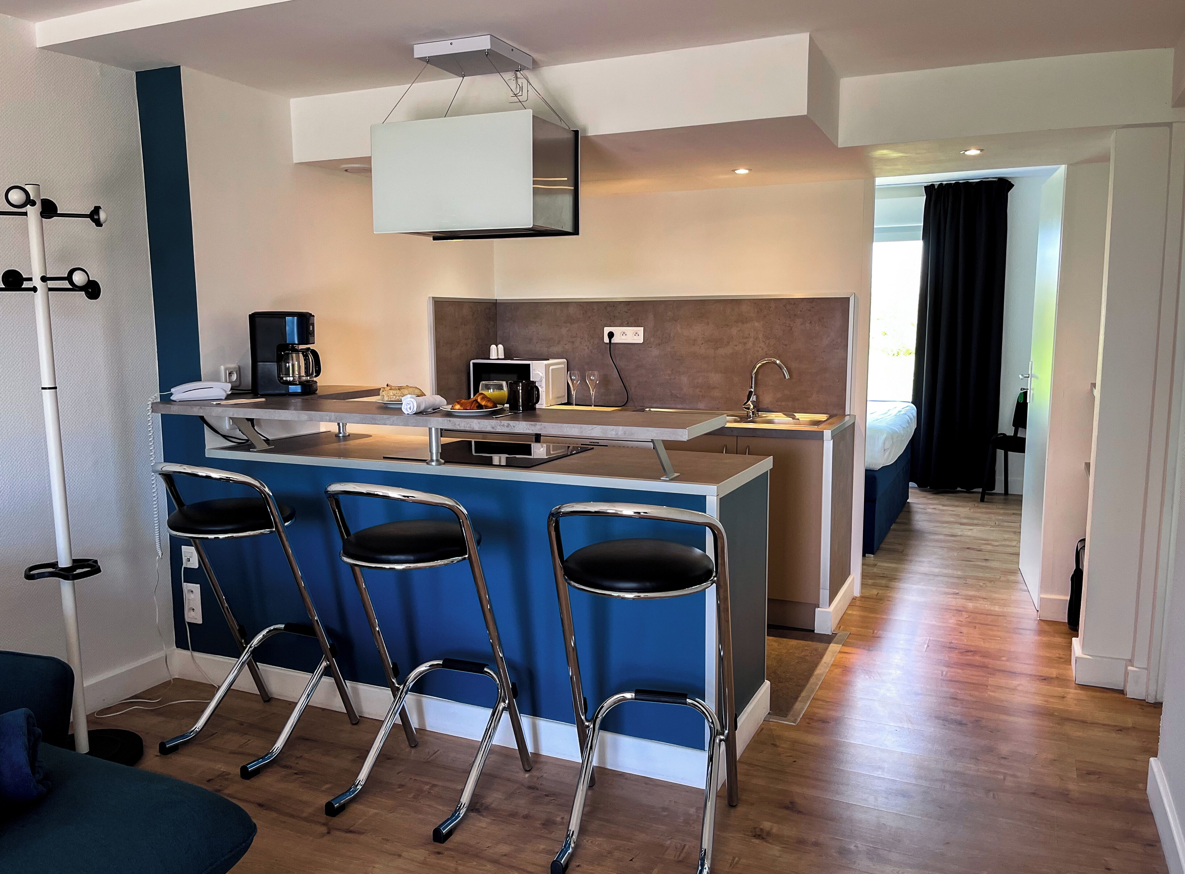 A modern kitchen with a central island, bar stools, a coffee maker, and a microwave.
