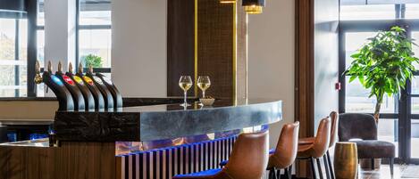 A modern bar area with a marble countertop, striped backrest, and leather bar stools.