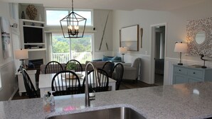 Una cocina moderna con encimeras de granito, un lavamanos de acero inoxidable y un comedor con mesa y sillas.