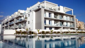 A modern hotel with multiple balconies, a swimming pool, and a clear blue sky. - Newly renovated dream apartment with all amenities (Torrox Costa)