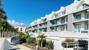 A modern hotel with multiple balconies, a paved walkway, and palm trees. - Newly renovated dream apartment with all amenities (Torrox Costa)