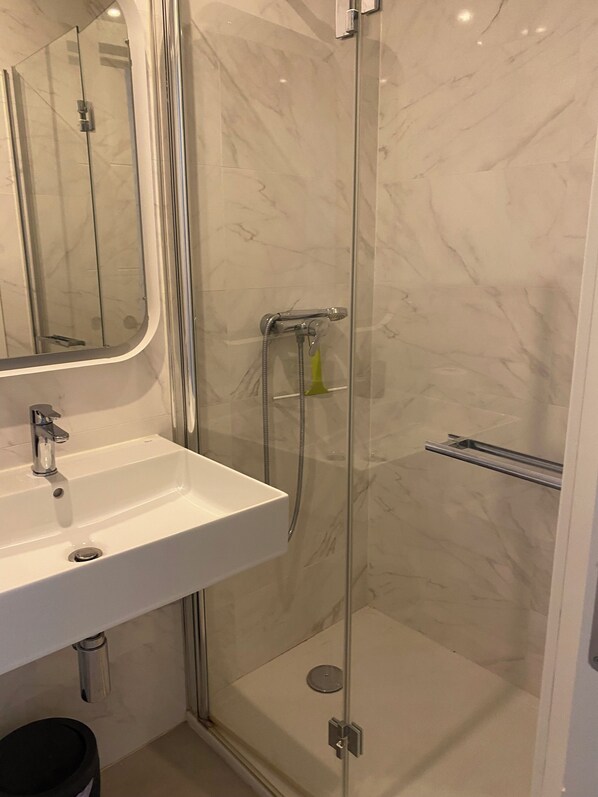 A bathroom with a glass-enclosed shower, a white sink, and a mirror. - Newly renovated dream apartment with all amenities (Torrox Costa)