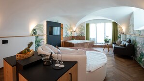 Een moderne, goed verlichte kamer met een rond bed, een klein ziteplaats voor een maaltijd en een zithoek met een bank en een tafel.