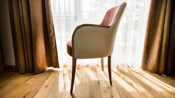 Une chaise dans une pièce dont le sol est en bois et qui est décorée de rideaux légers et transparents.