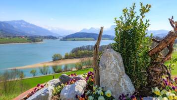 Ein malerischer Blick auf einen See mit Bergen im Hintergrund, umgeben von Felsen und bunten Blumen.