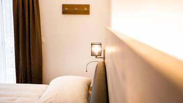 Habitación de hotel con una cama, una mesita de noche con una lámpara y un panel de madera encima de la mesita.
