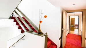Een moderne trap met een rood tapijt, een vaas met bloemen en uitzicht op een kamer met een rood tapijt.